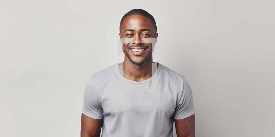 Radiant African American man with a captivating smile, wearing a light grey shirt, against a clean white background.