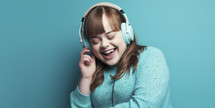 Joyful young woman with Down syndrome wearing a teal sweater with heart patterns, listening to music on white headphones, eyes closed and a big smile, against a turquoise background.