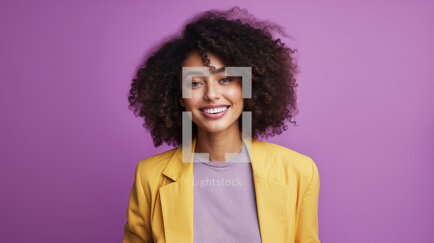 Vivacious young woman with curly hair wearing a yellow blazer over a lilac top, against a purple background.