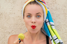 woman with her hair wrapped in a towel holding a macaron 