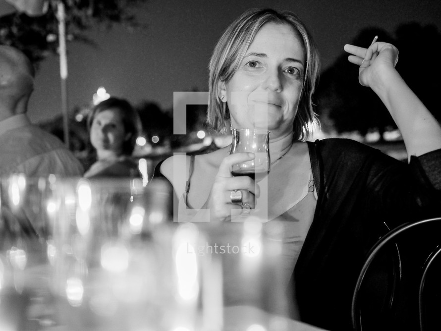 Woman at dinner party outdoor in summer smoking and drinking wine