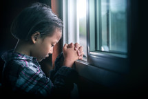 a child praying in a window 