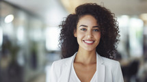 Cheerful young businesswoman with curly hair in office.