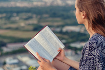 a woman holding a Bible outdoors 