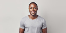 Radiant African American man with a captivating smile, wearing a light grey shirt, against a clean white background.