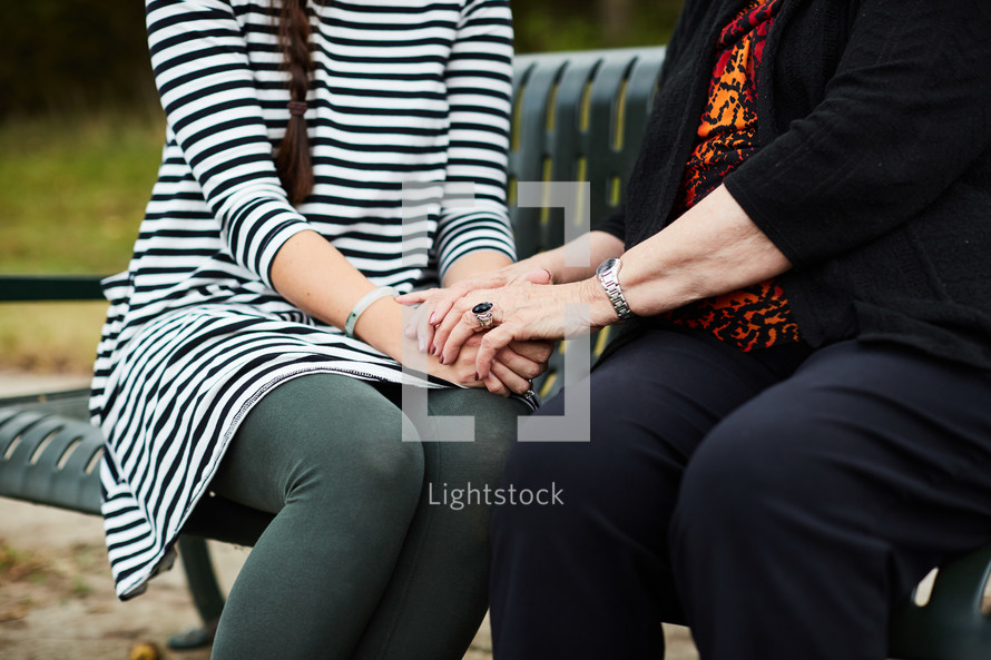 elderly woman praying with a young woman 