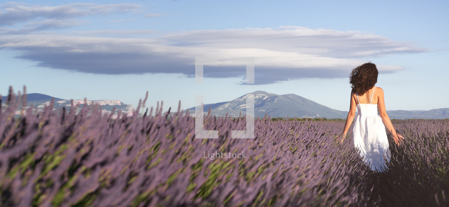 a woman walking through a field of lavender 