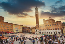 Siena, Italy - September 11, 2019: Sunset over tourists inside Piazza del Campo in a cloudy day, Siena, region of Tuscany, Italy