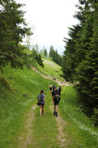 people walking up a worn path on a mountainside 