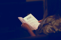 a woman reading a church bulletin 