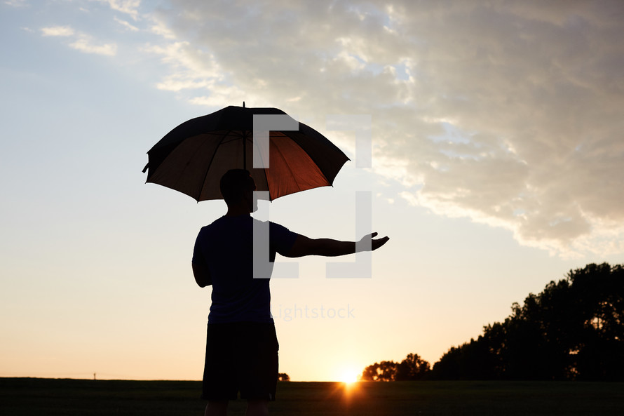 silhouette of a man holding an umbrella 