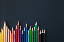 row of colored pencils on a black background 