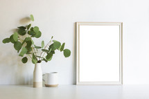vase of eucalyptus twigs and blank frame 