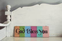 God Bless You sign on a white bench 