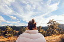 woman looking out at a mountain forest 