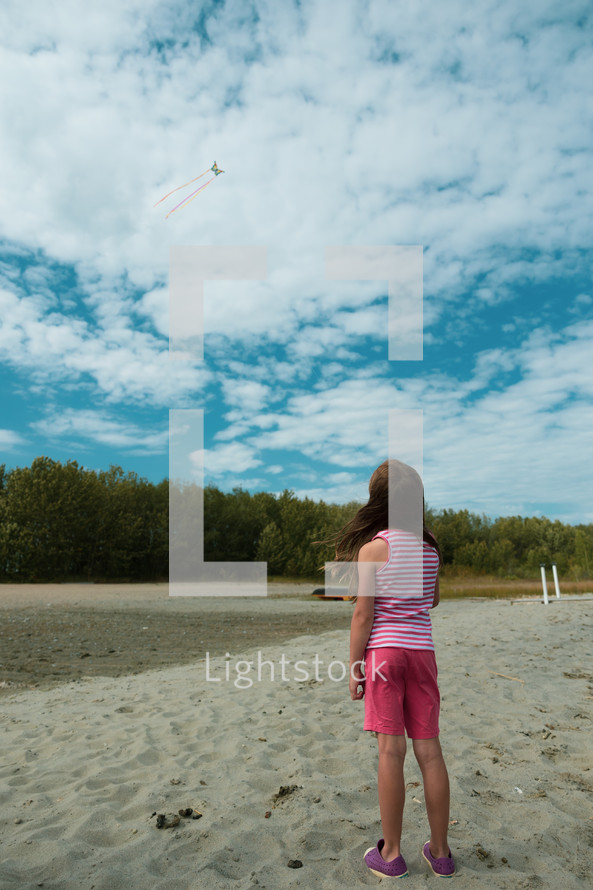 a child flying a kite on a beach 