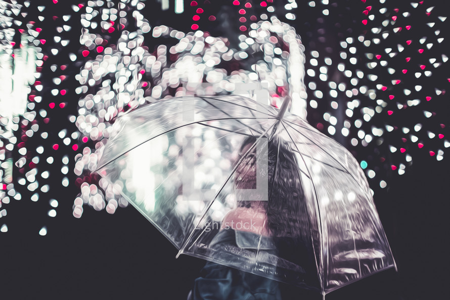 a woman standing under an umbrella and raining Christmas lights 
