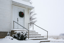 The entrance of an old country church in the snow.