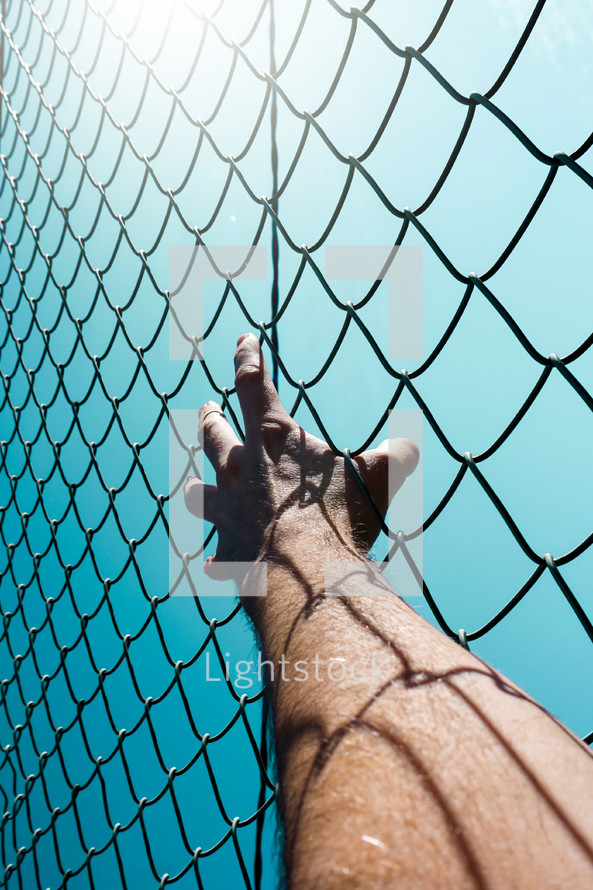 hand grabbing a metallic fence feeling freedom