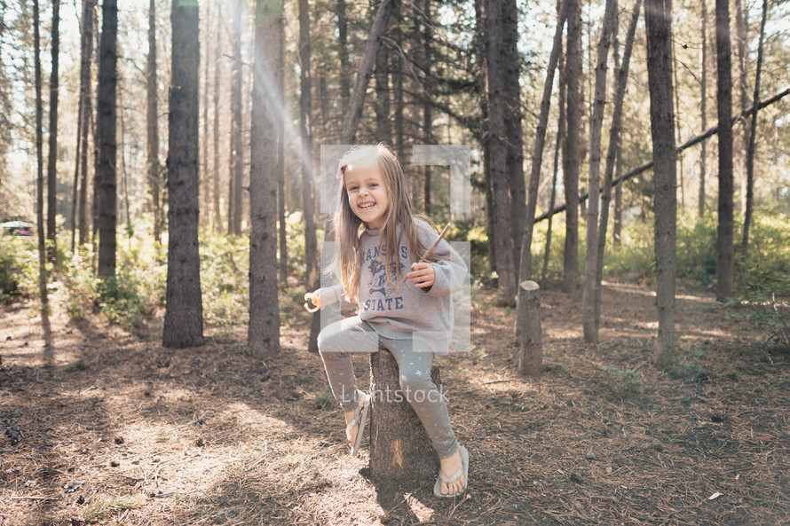 a girl sitting on a tree stump 