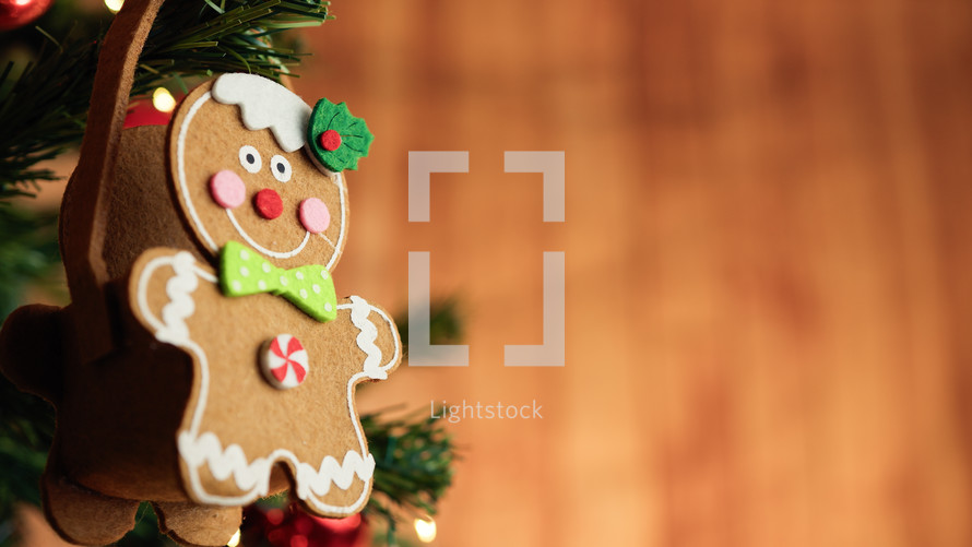 Gingerbread man decoration on a Christmas tree with falling snow 