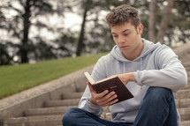 Christian worship and praise. A young man is praying and reading the bible in the evening