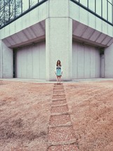 A woman standing in front of a building with a path.