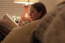 a woman reading on a couch 