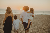 a family walking on a beach at sunset 
