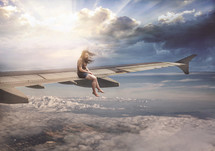 a woman sitting on the wing of an airplane 