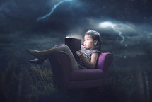 A little girl is scared and reading during a storm