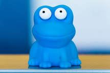 Toy blue flog with big white eyes, smiling
