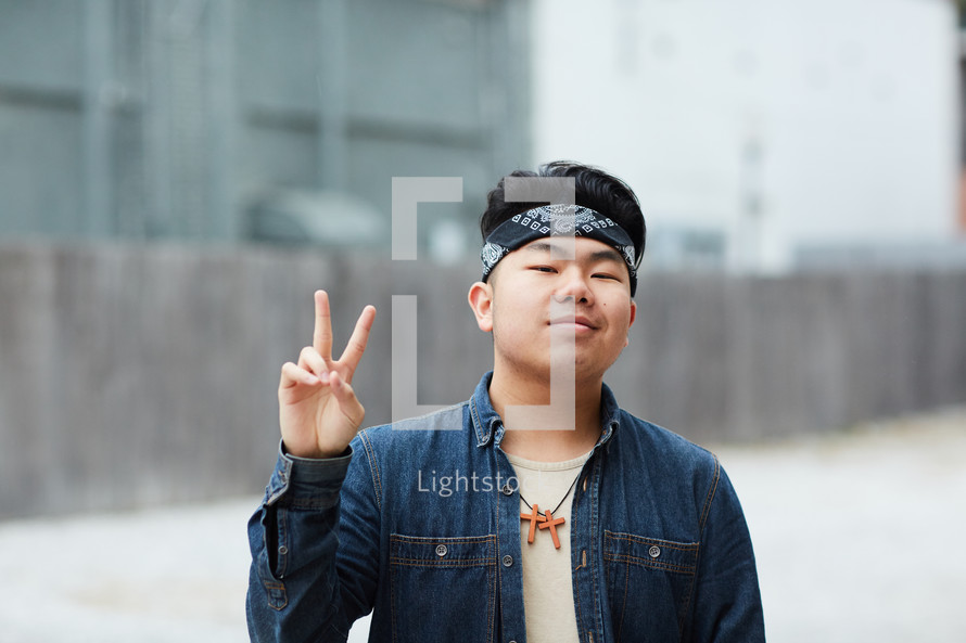 teen boy making a peace symbol 