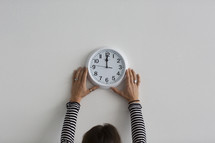 A person hanging a wall clock.