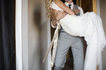 groom carrying his bride over the threshold 
