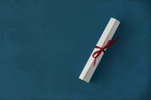 rolled up diploma on blue background.