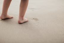 toddler's feet on a sandy beach 