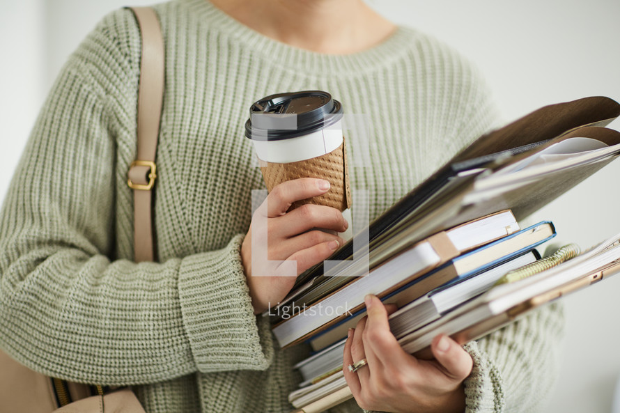 a student holding a coffee cup and books 