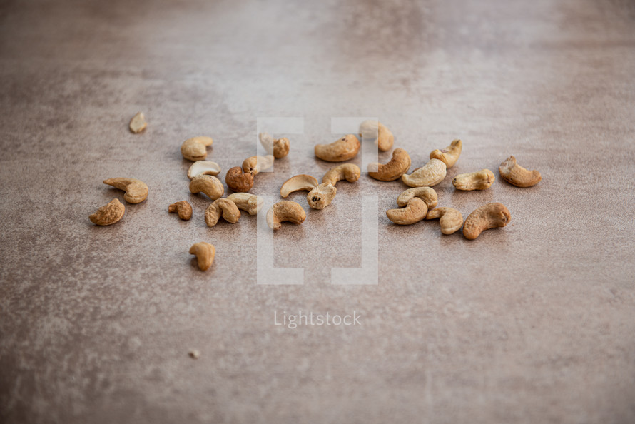 lots of fried cashews nuts scattered on grey background with copy space