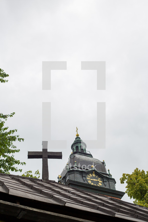 A cross in front of a church steeple.