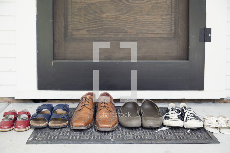row of a families shoes on a door mat 