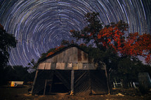 swirling stars in a night sky behind an old shed