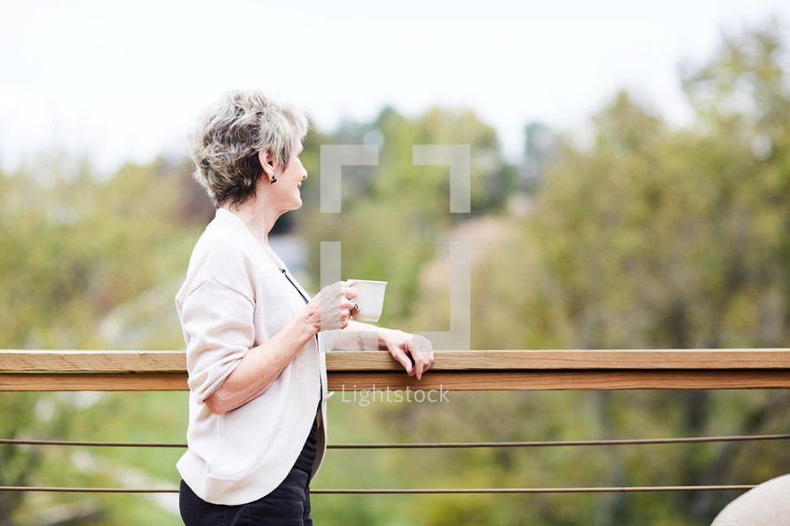 an elderly woman looking over a railing thinking 