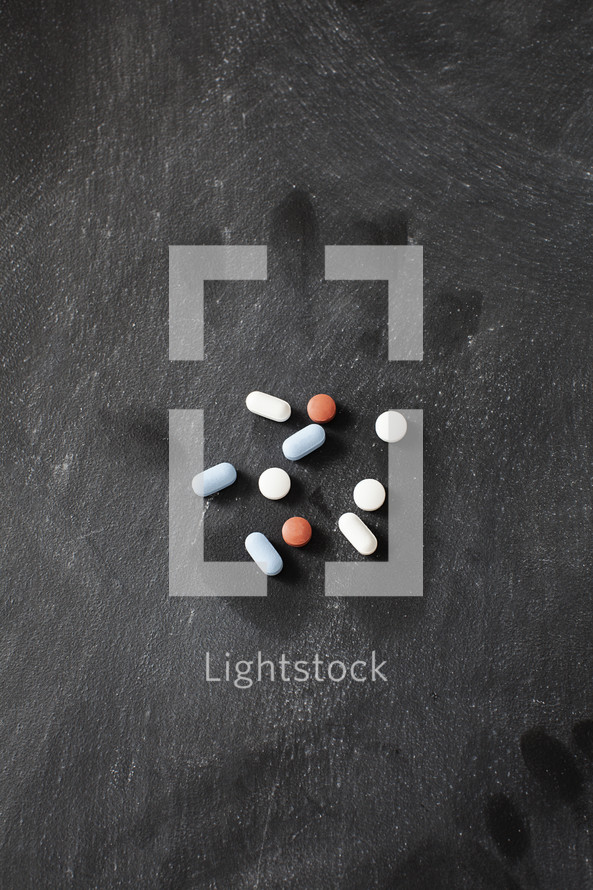 pills on a dark table with faint handprint mark