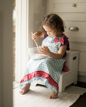 Little girl in apron baking in kitchen