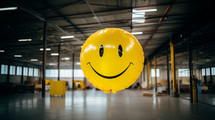 Yellow smiley face balloon in warehouse. Workplace happiness concept. 