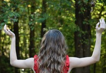 teen girl with arms raised standing in nature 