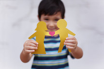 Asian child holding paper dolls 