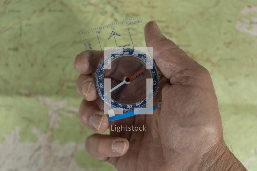 A man holding a compass with map background