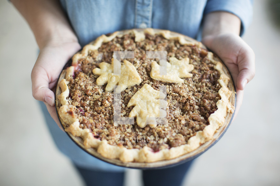 A woman's hands holding a freshly baked pie.